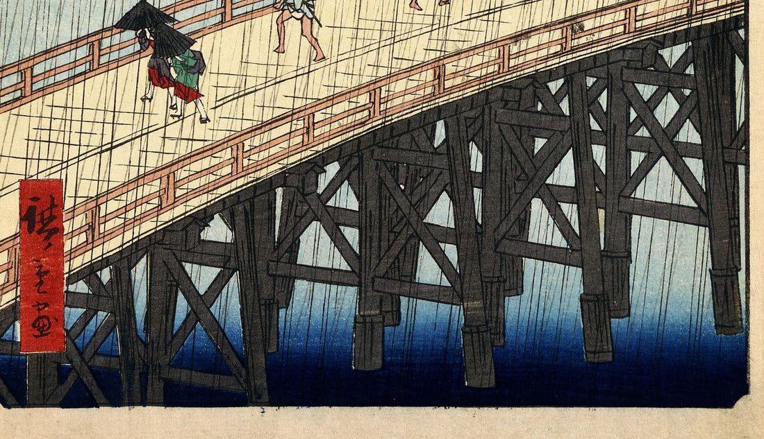 Detail of Hiroshige's bridge: figures crossing in the rain under umbrellas, the pale plank deck above a dark timber trestle.